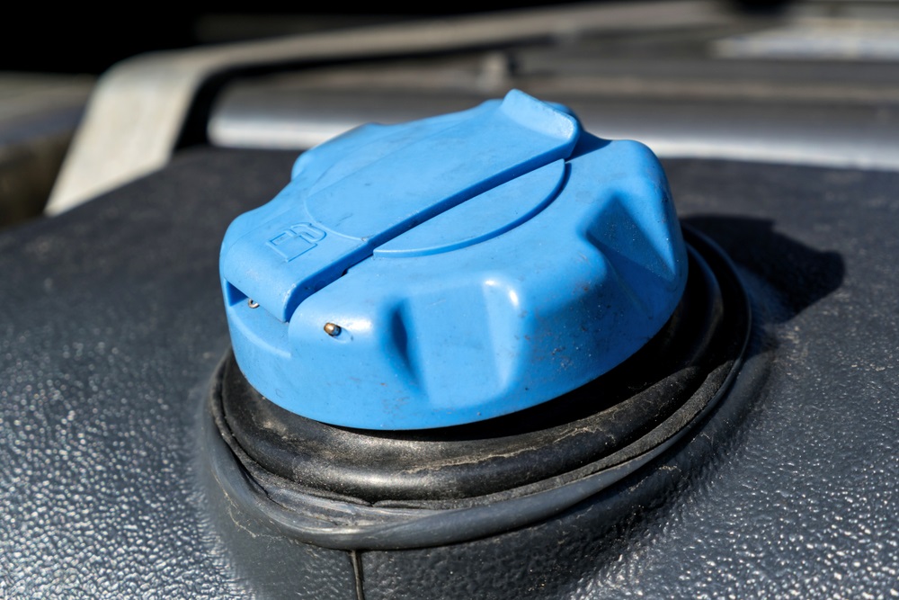 A container of diesel exhaust fluid next to a gasoline engine, illustrating potential risks and safe practices.