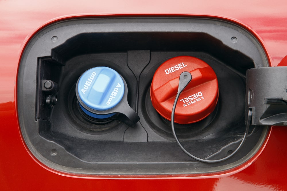 A driver refilling a diesel vehicle with AdBlue at a fuel station.