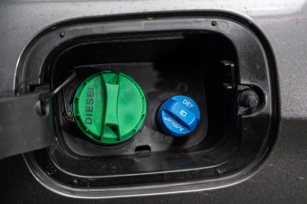 A driver refilling a diesel vehicle with AdBlue at a fuel station.