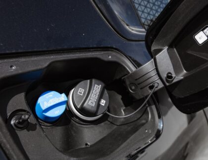 A driver refilling a diesel vehicle with AdBlue at a fuel station.