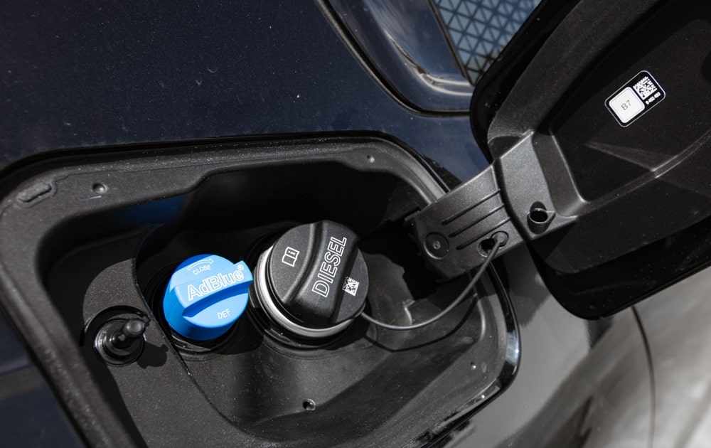 A driver refilling a diesel vehicle with AdBlue at a fuel station.