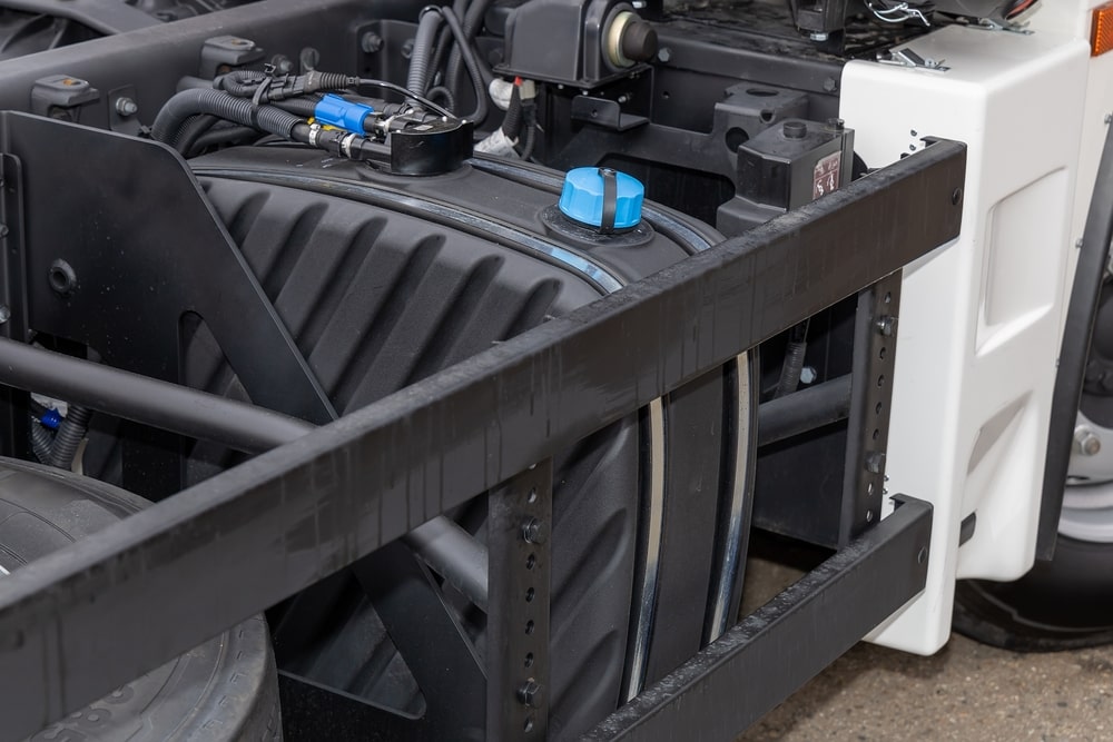 A container of Diesel Exhaust Fluid being poured into a truck’s DEF tank.