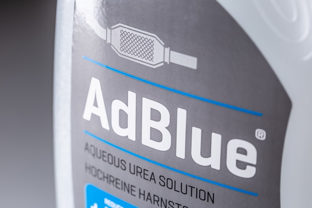 A driver pouring AdBlue into a diesel car’s AdBlue tank.
