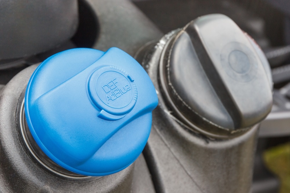 A fuel nozzle with an AdBlue label near a petrol engine.