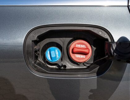 A driver pouring AdBlue into a diesel car’s AdBlue tank.