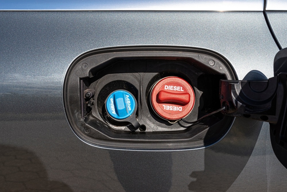 A driver pouring AdBlue into a diesel car’s AdBlue tank.