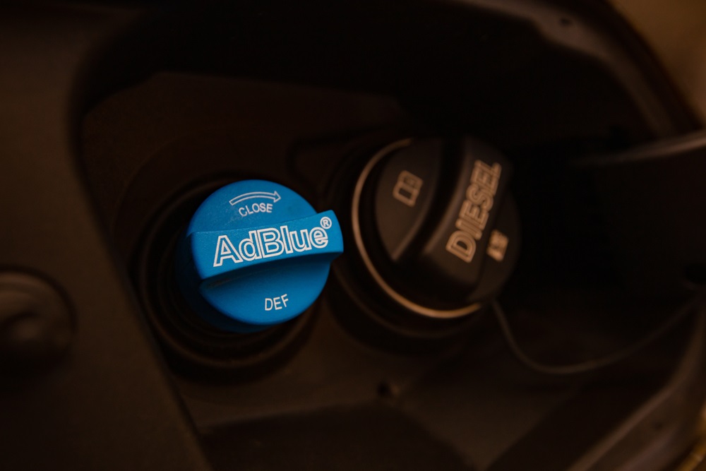 A driver pouring AdBlue into a diesel car’s AdBlue tank.