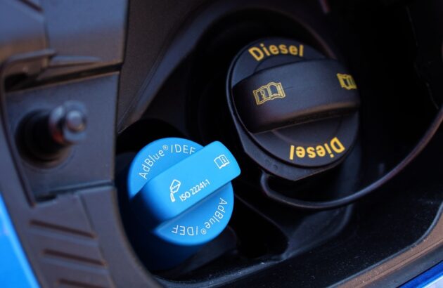 A fuel nozzle with an AdBlue label near a petrol engine.