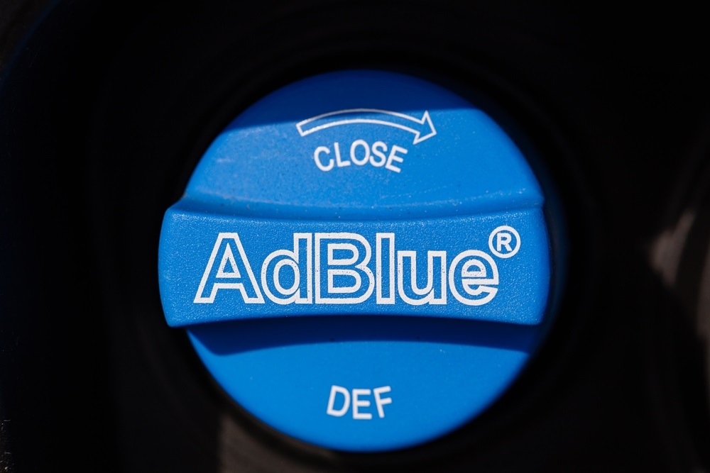 A fuel nozzle with an AdBlue label near a petrol engine.