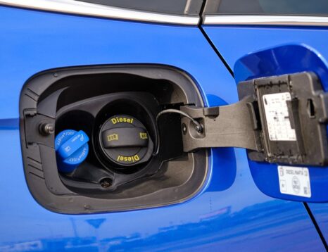 Technician checking diesel exhaust fluid with a handheld refractometer next to a truck DEF tank