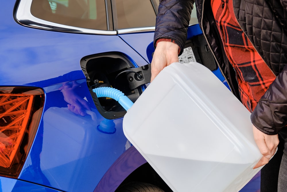 Technician checking diesel exhaust fluid with a handheld refractometer next to a truck DEF tank