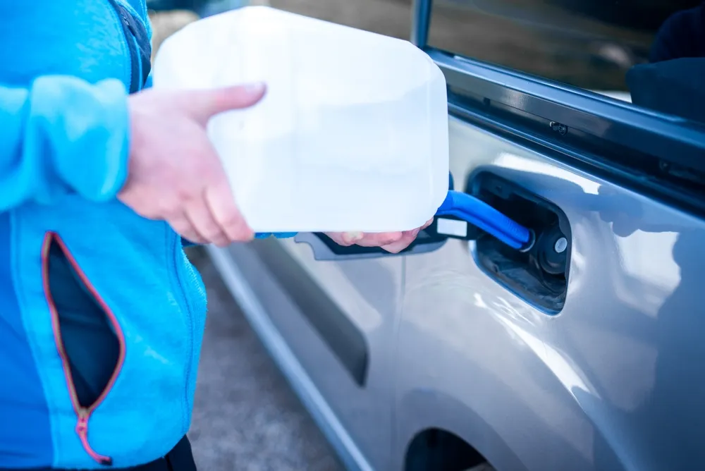 Diesel vehicle dashboard showing AdBlue warning with DEF refill container nearby