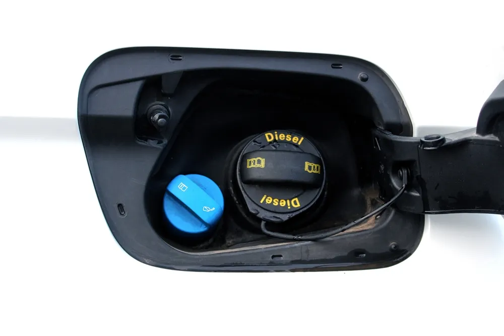 Diesel vehicle dashboard showing AdBlue warning with DEF refill container nearby
