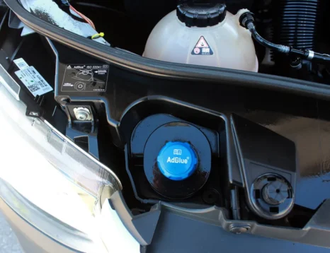 Diesel vehicle dashboard showing AdBlue warning with DEF refill container nearby