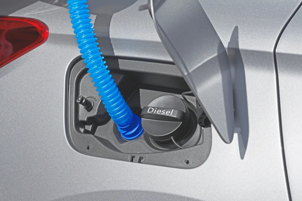 Diesel vehicle dashboard showing AdBlue warning with DEF refill container nearby