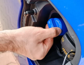 Diesel vehicle being refilled with AdBlue diesel exhaust fluid near a fuel pump