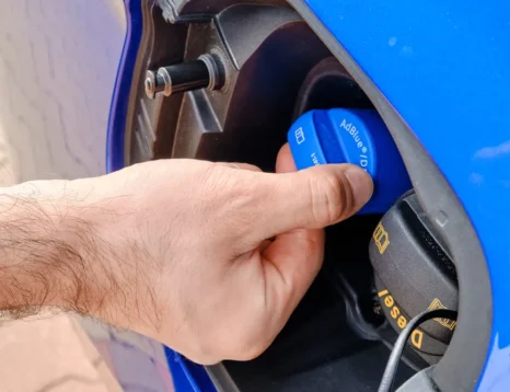 Diesel vehicle being refilled with AdBlue diesel exhaust fluid near a fuel pump
