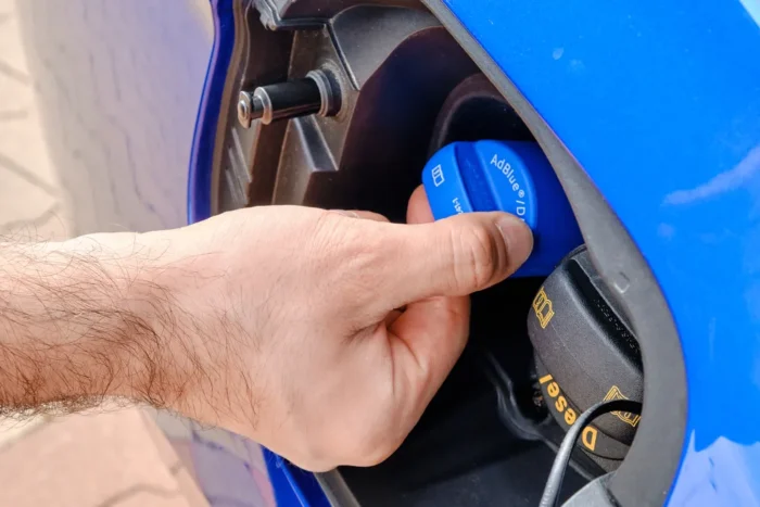 Diesel vehicle being refilled with AdBlue diesel exhaust fluid near a fuel pump