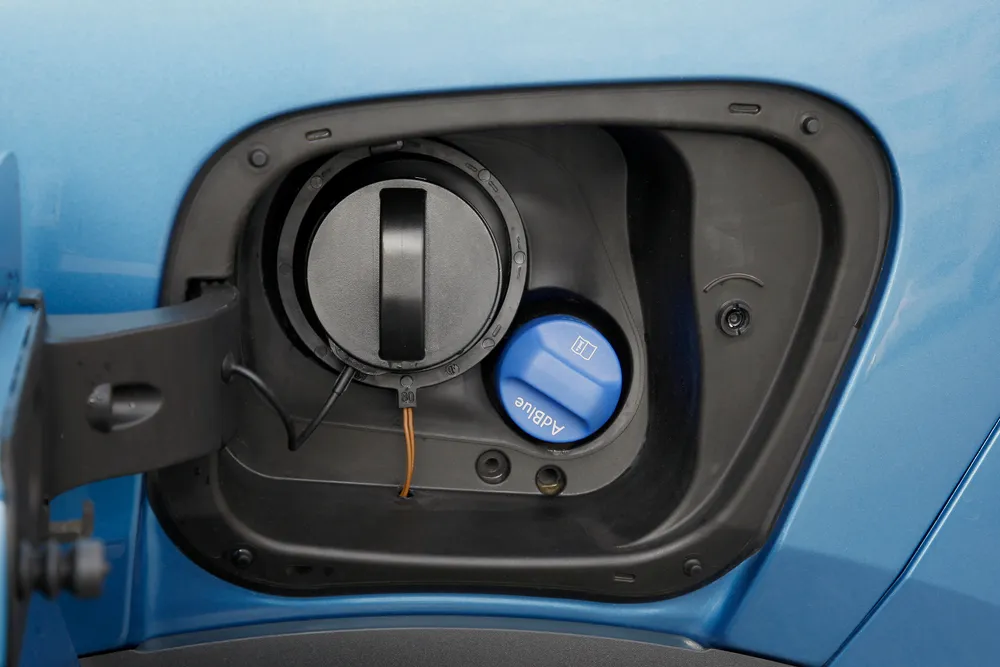 Diesel vehicle being refilled with AdBlue diesel exhaust fluid near a fuel pump