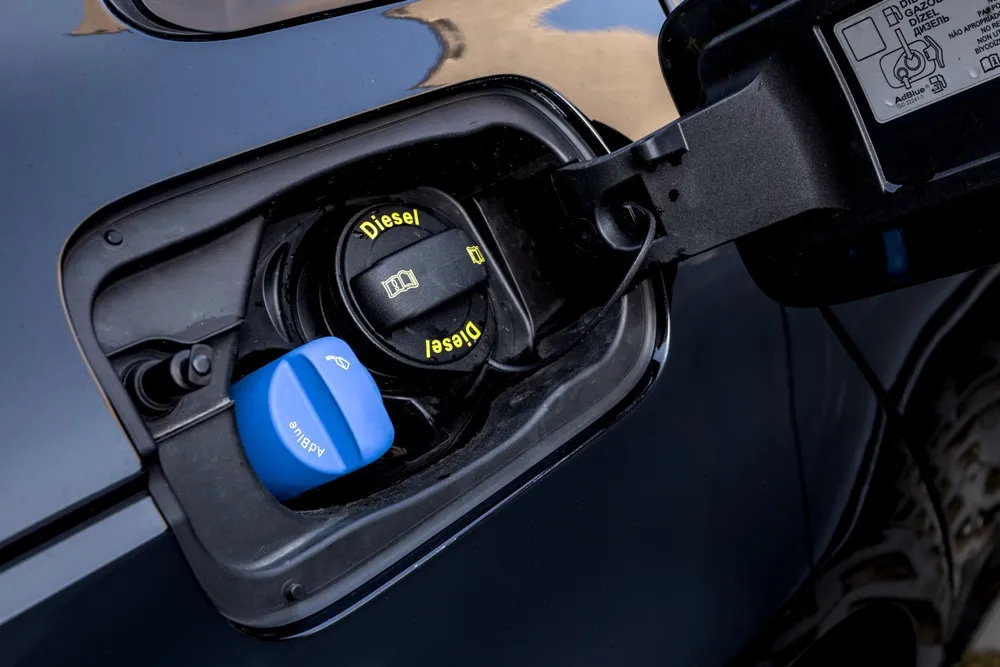 Diesel vehicle being refilled with AdBlue diesel exhaust fluid near a fuel pump